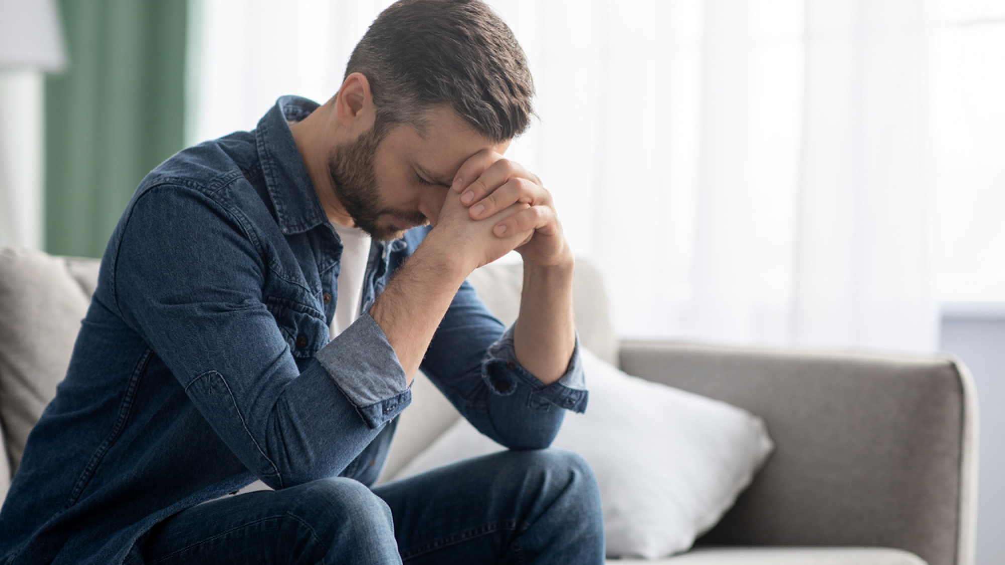 Depressed,Middle-aged,Man,Sitting,On,Couch,In,Living,Room,,Leaning